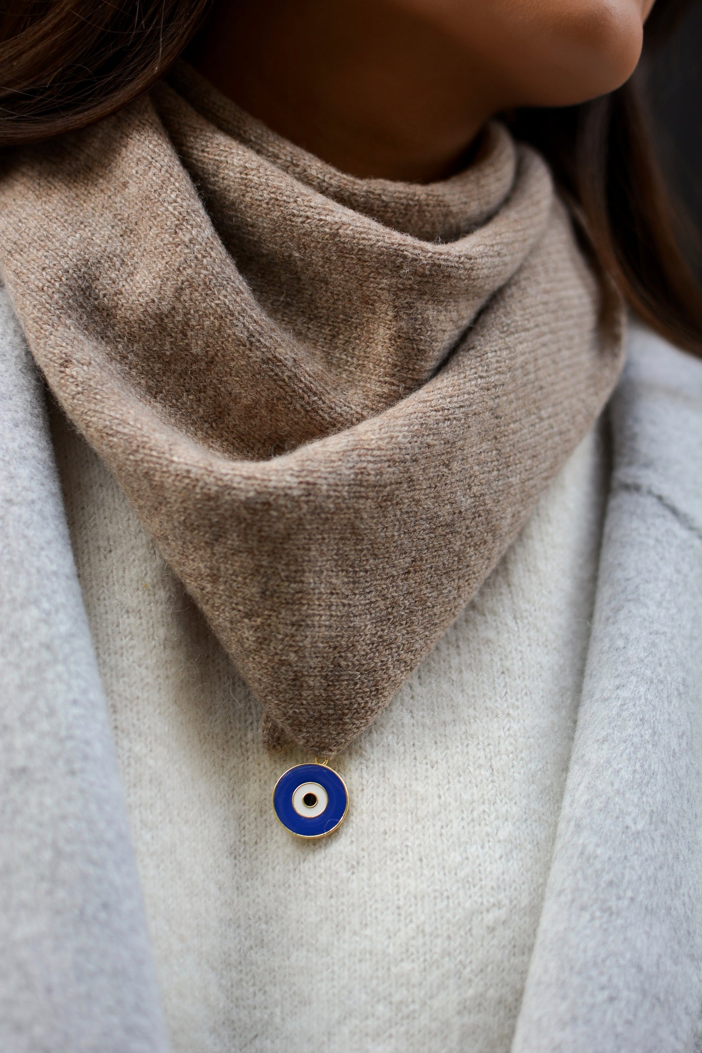 photo zoomée du bandana en laine taupe avec charm oeil porté par le modèle 