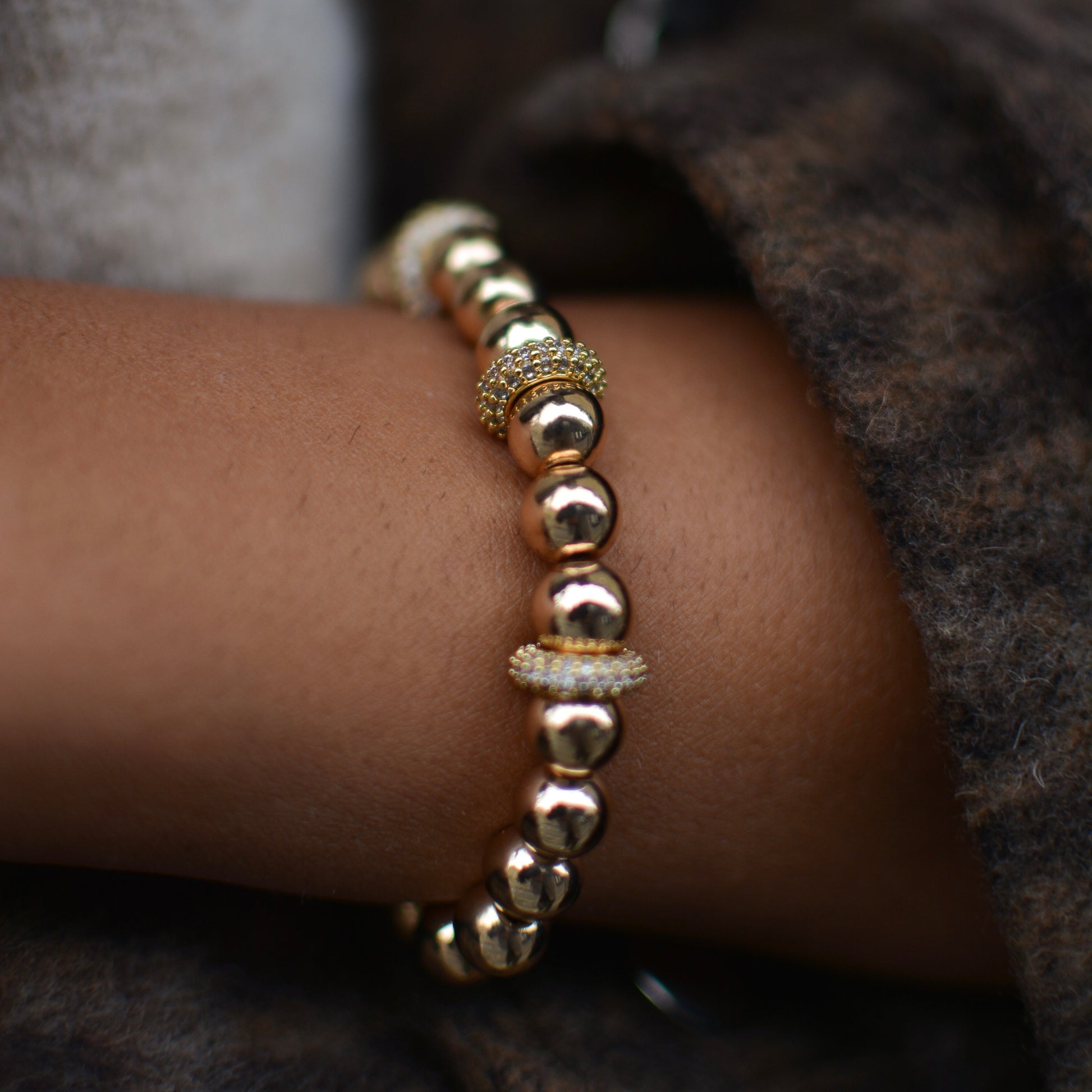 bracelet en hematite en forme de perles rondes dorées avec zircons porté par le modèle