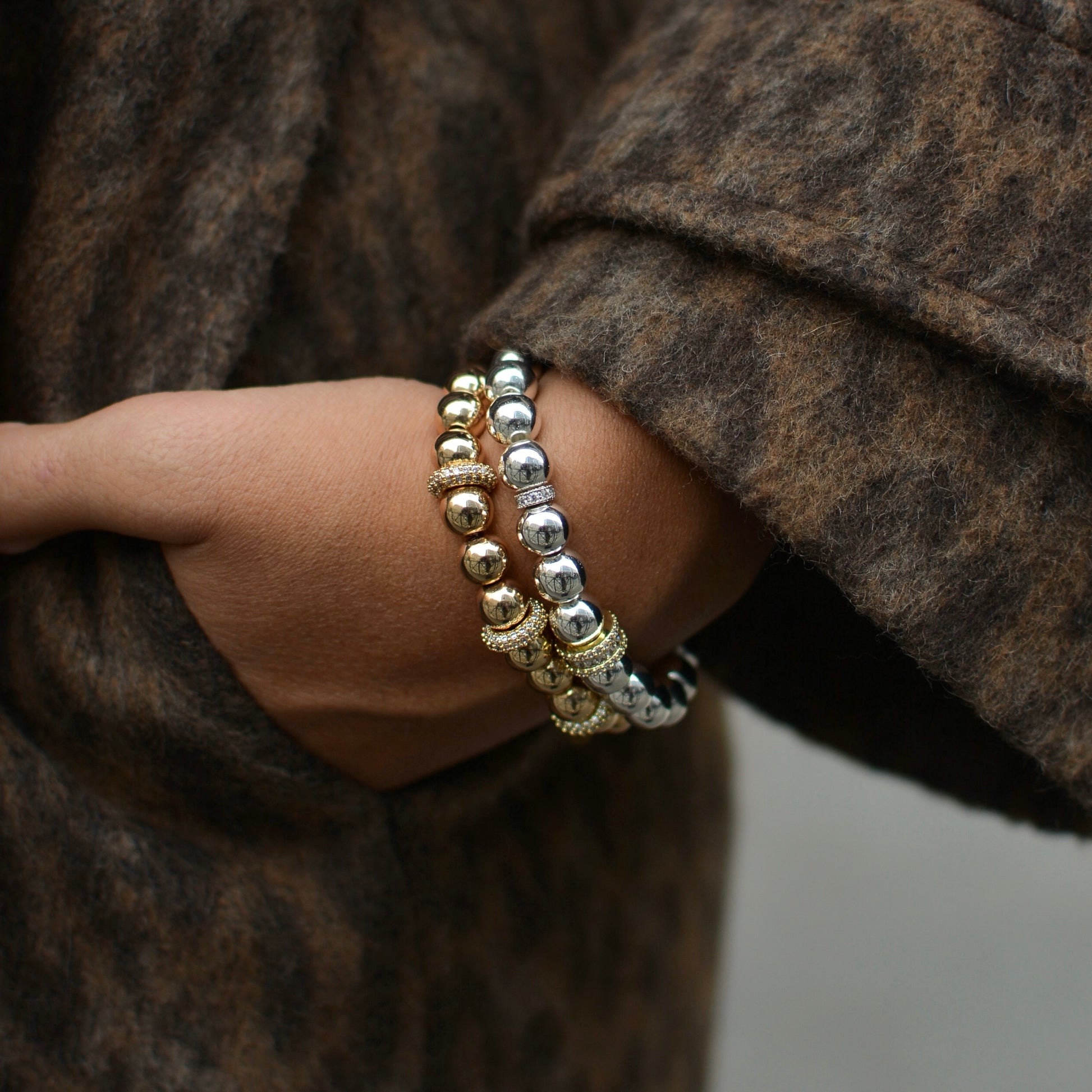 bracelet en hématite doré porté par le modèle en accumulation. bracelet en forme de perles rondes. 