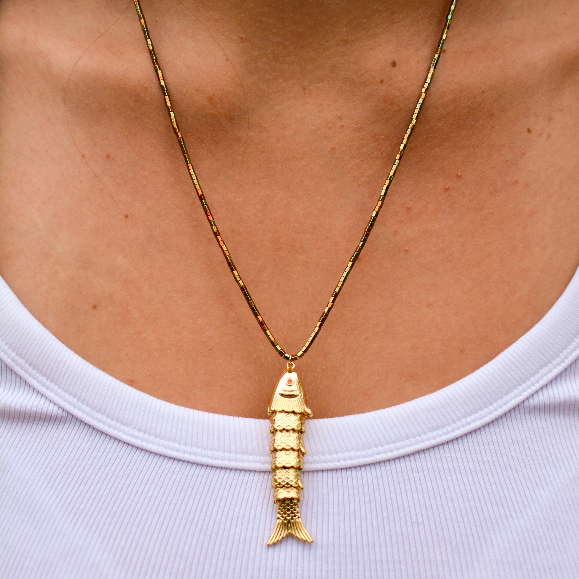 Collier en pierres semi précieuses d'hématite plaquées or et résistantes à l'eau orné d'un charm poisson plaqué or. 