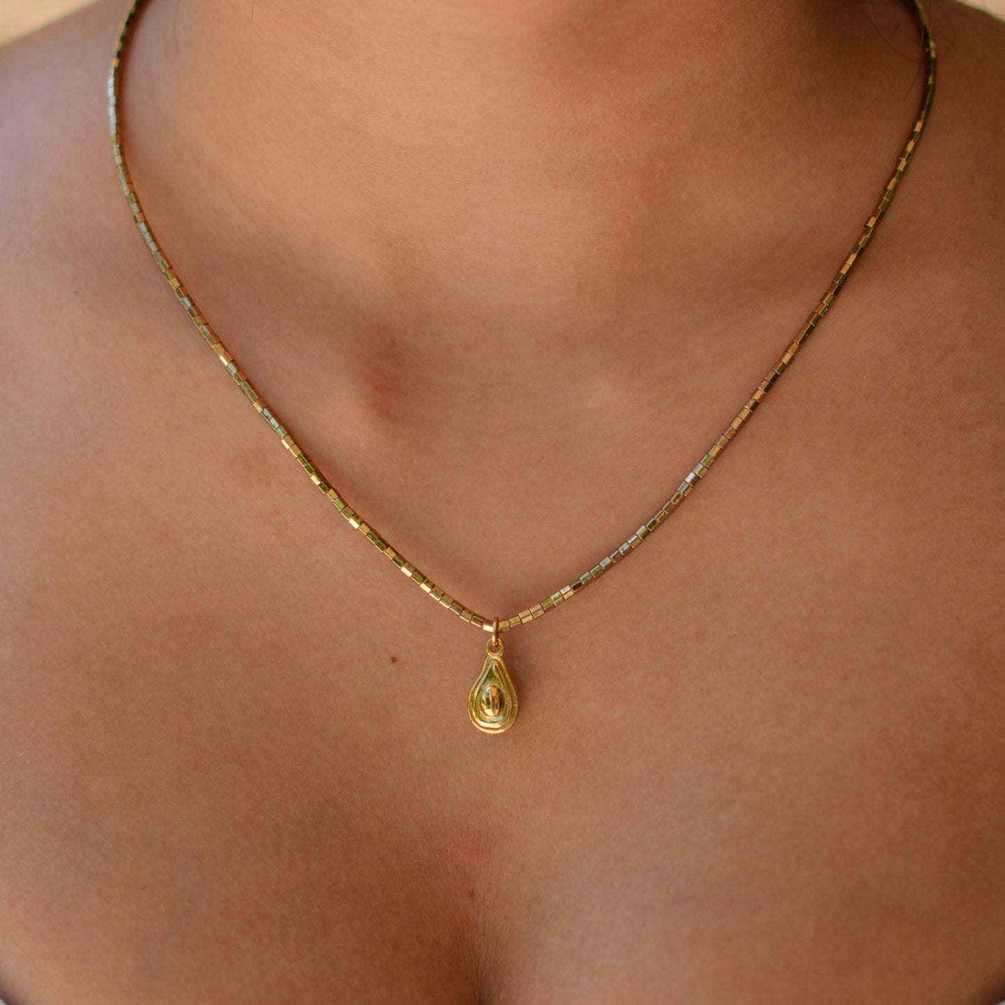 Collier plaqué or en pierres semi précieuses d'hématite résistantes à l'eau orné d'un charm avocat en plaqué or. 