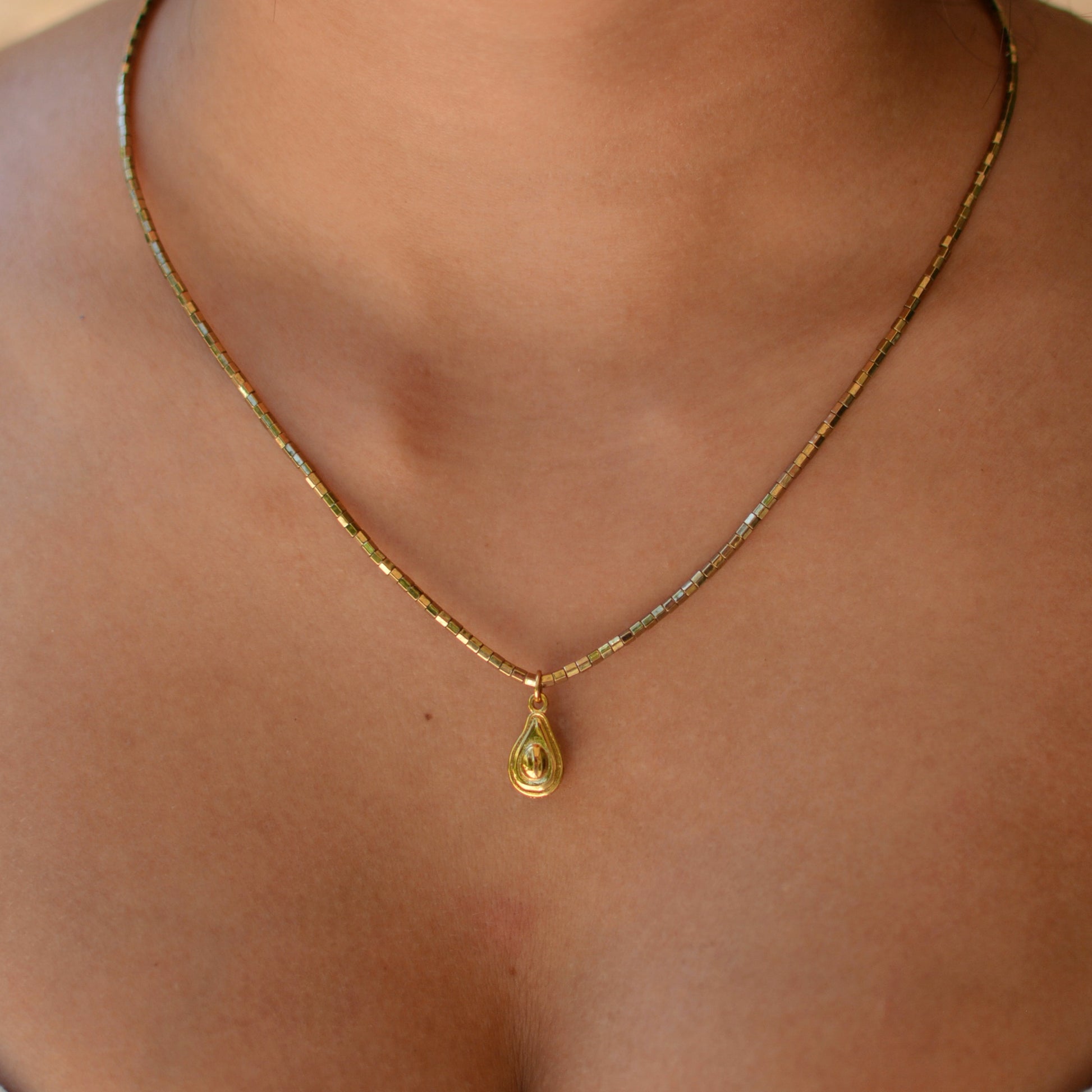 Collier plaqué or en pierres semi précieuses d'hématite résistantes à l'eau orné d'un charm avocat en plaqué or. 