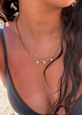 collier doré perlé Riviera avec trois charms dorés porté par le modèle 