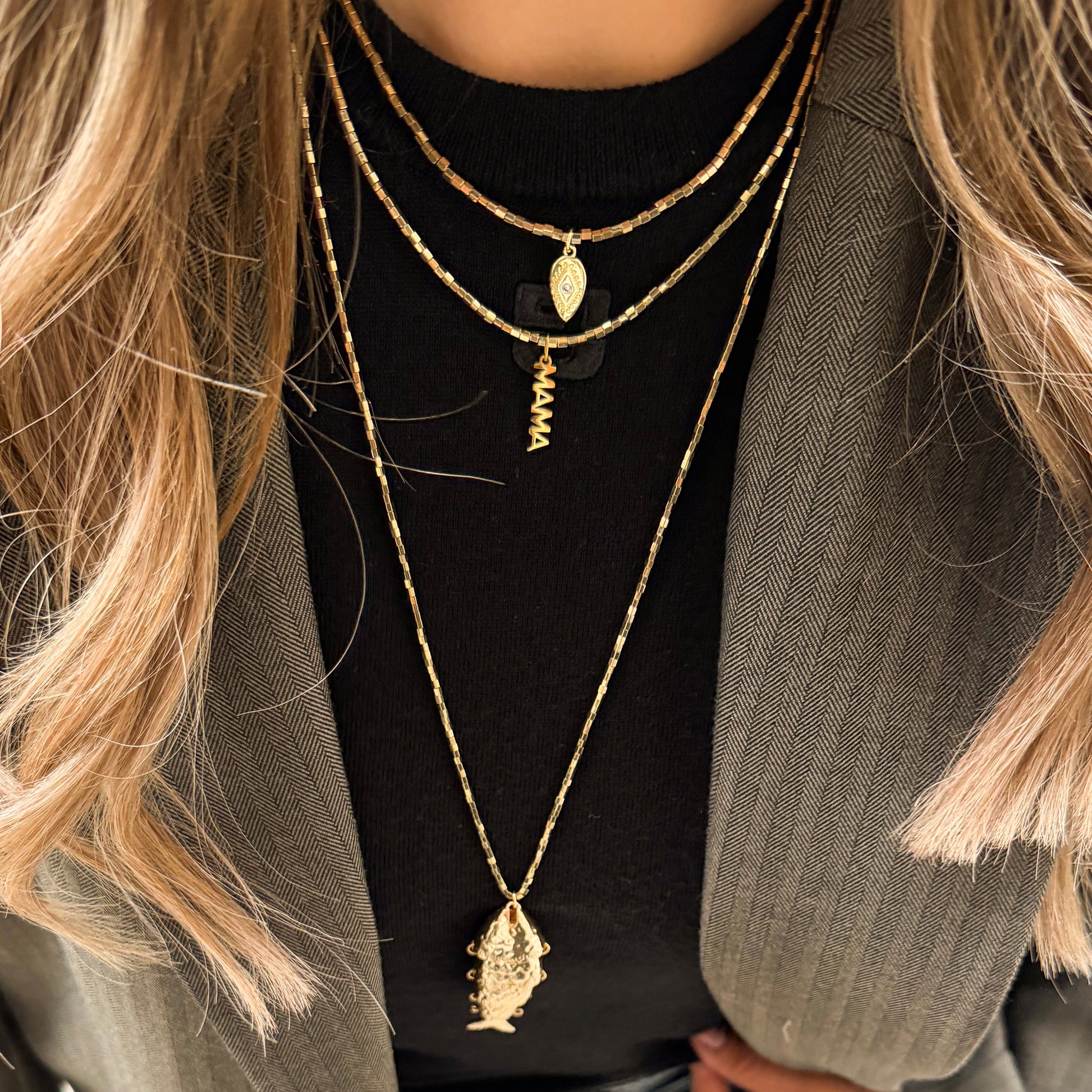 collier court en hématite doré avec charm doré porté en accumulation par le modèle
